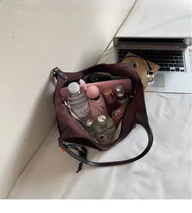 Détail de l'intérieur spacieux du cabas en daim marron avec objets du quotidien