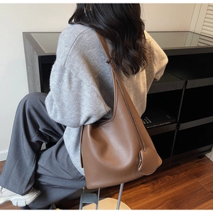 Brown lychee grain leather bucket bag shown on shoulder for a slouchy oversized look