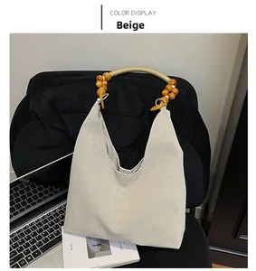 Détail du sac cabas beige avec poignée en perles de bois posé sur une chaise