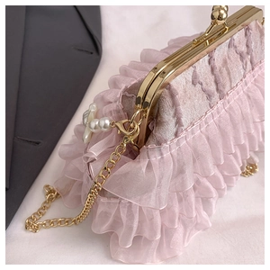 Detailed macro view of pink pleated lace evening bag with golden metal chain strap