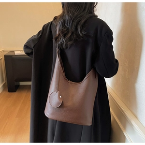 Detail shot of deep brown lychee grain leather hobo bag on model's shoulder