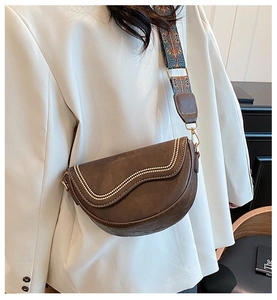 Detail of vintage brown saddle bag with ethnic woven strap and white bead trim