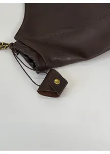 Détail du sac cabas en cuir marron foncé avec cordon de serrage et chaîne dorée chic