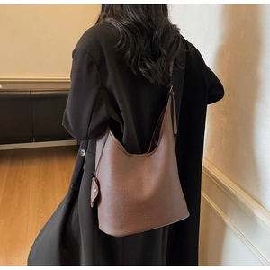 Close-up of deep brown lychee texture leather bucket bag with shoulder strap detail