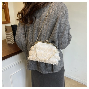 Detail of white pleated lace evening bag with elegant pearl handle and gold chain