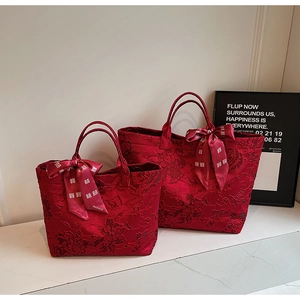 Detail der roten Jacquard-Sticktaschen mit Blumenmustern und Seidenbandgriffen am Henkel