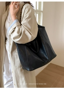 Détail du sac cabas noir avec texture cuir mat et bandoulière en chaîne dorée