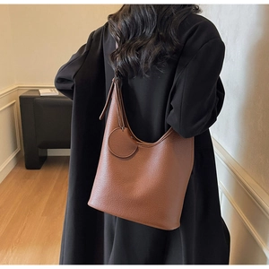 Detailed view of brown lychee grain hobo bag with round charm pendant on a model