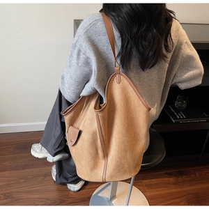 Lifestyle shot of large caramel suede tote bag and matching mini pouch on woman shoulder