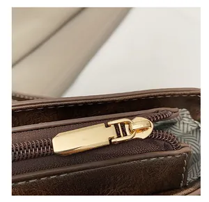 Detail of smooth gold metal zipper on a dark brown leather crossbody saddle bag