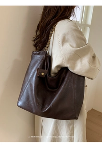 Détail d'un cabas en cuir marron foncé avec surface texturée et bandoulière en chaîne