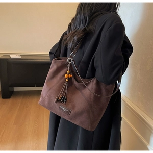 Détail d'un sac cabas en daim marron avec pendentif à pampilles perlées et texture rétro