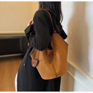 Detail of large vintage tote bag in caramel suede with dark brown leather trim and slim strap