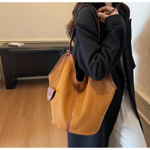 Brown suede tote bag shown on model shoulder highlighting the soft texture and large size