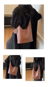 Close-up of brown litchi leather bucket bag with a round coin purse charm on the strap