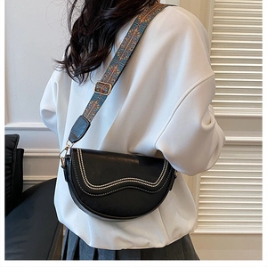 Detail of a black saddle bag with gold studs and a colorful woven wide shoulder strap