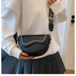 Close-up of black crescent saddle bag with wavy stitching and ethnic jacquard wide strap