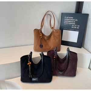 Trois sacs cabas en daim mat en camel, marron et noir avec des pompons décoratifs