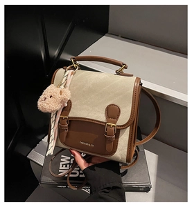 Détail du sac en toile avec lanières en cuir, logo et pendentif ours en peluche