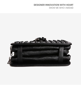 Détail du sac accordéon en cuir noir avec trois compartiments et des clous
