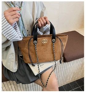 Close-up of brown suede tote bag featuring gold hardware and black leather handles