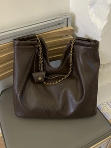 Sac cabas en cuir marron foncé avec double anses en chaîne et logo embossé sur le devant