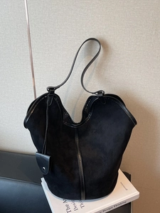 Large vintage black suede tote bag with leather trim on white books and beige background