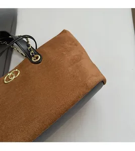 Close-up of brown suede tote bag with golden rings and leather stitching detail