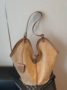 Retro large brown suede tote bag with leather trim and shoulder strap on minimalist books