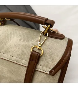 Détail du sac en toile beige avec lanière en cuir marron et boucle dorée de haute qualité