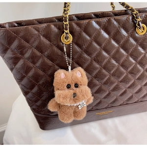 Détail d'un joli chien en peluche avec collier de perles sur un sac cabas