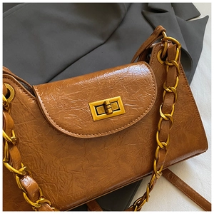 Macro detail of brown wrinkled leather texture and golden metal twist lock on shoulder bag