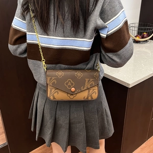 Detail of a brown textured crossbody bag featuring vintage floral patterns and gold chain strap