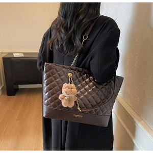 Détail du sac cabas matelassé marron avec bandoulière chaîne et charme d'ours en peluche