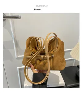 Dettaglio borsa sottobraccio in pelle scamosciata marrone con occhielli dorati e manici