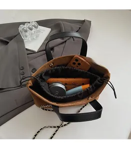 Detailed view of brown suede tote bag featuring a drawstring closure and spacious interior