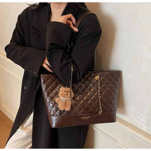 Close-up of quilted coffee tote bag with gold chain strap and plush bear charm