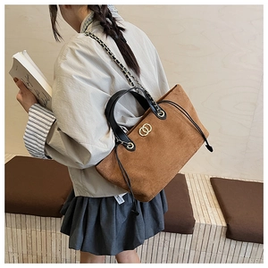 Detail of suede tote bag with black handles and golden double-ring metal buckle