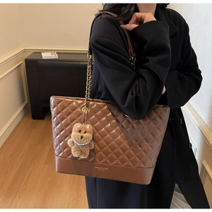 Détail du cabas matelassé marron avec bandoulière chaîne et accessoire ours en peluche