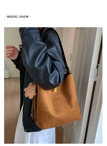 Detail of dark brown suede bucket bag featuring a gold buckle and cute bear charm