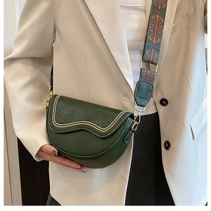 Dark green saddle bag with beaded trim and patterned wide shoulder strap shown on a model