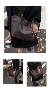 Detail der dunkelbraunen Totebag mit Lederstruktur, Doppelriemen und Plüschbär-Anhänger
