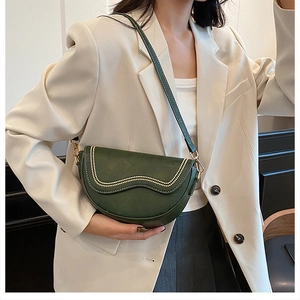 Detail of dark green saddle bag with gold studded flap and wave edge design
