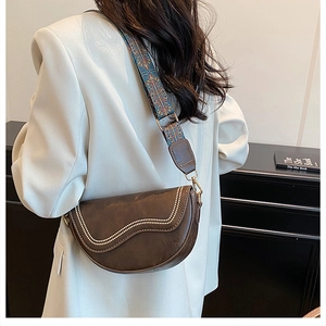 Detail showing vintage brown saddle bag with wave rivets and colorful woven wide strap
