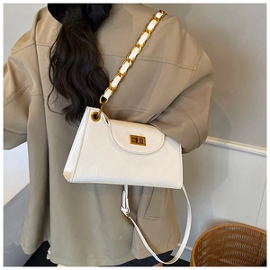 Detail of white vintage textured crossbody bag with gold chain strap and turn-lock closure