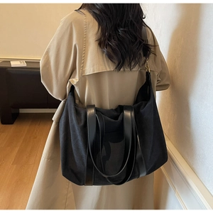 Large black canvas tote bag with leather straps shown on model for daily commuting