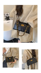 Detail of the vintage black wrinkled leather texture and gold metal chain strap of the bag