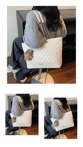 Close-up of white quilted leather tote bag featuring gold chain strap and teddy bear charm
