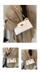 Detail of white glossy pleated shoulder bag with gold square twist lock and chain strap