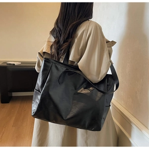 Detailed side view of a large black tote bag with smooth texture and sturdy shoulder straps